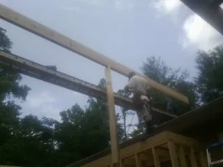 Carpenter setting a ridge beam over a new addition frame — Ice Dam Removal by Roofing Brothers in Northpoint