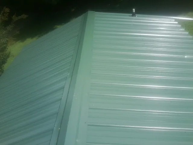 New green metal panels meeting at the ridge of a roof — Flat Roof Repair work by our crew in Northpoint