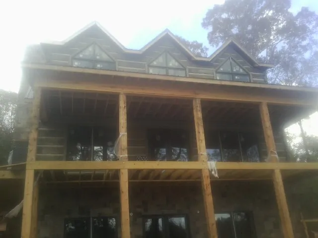 Dormers and porch framing on a large log home under construction — Roof Coating work by our crew in Northpoint