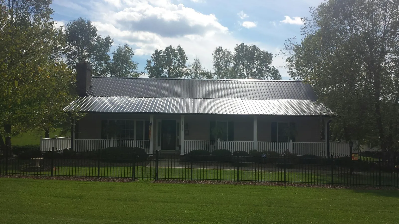 Gray metal roof on a brick ranch with a full width front porch — Gutter Guard Installation work by our crew in Northpoint