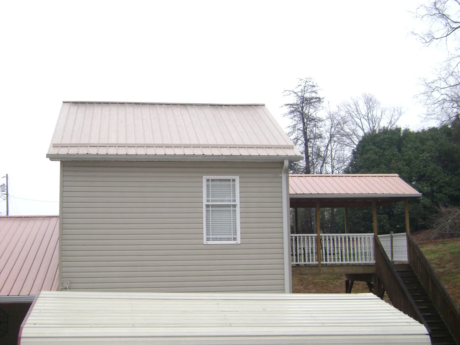 Tan metal roofs on a two story addition and attached porch, from a Roof Replacement job in Northpoint