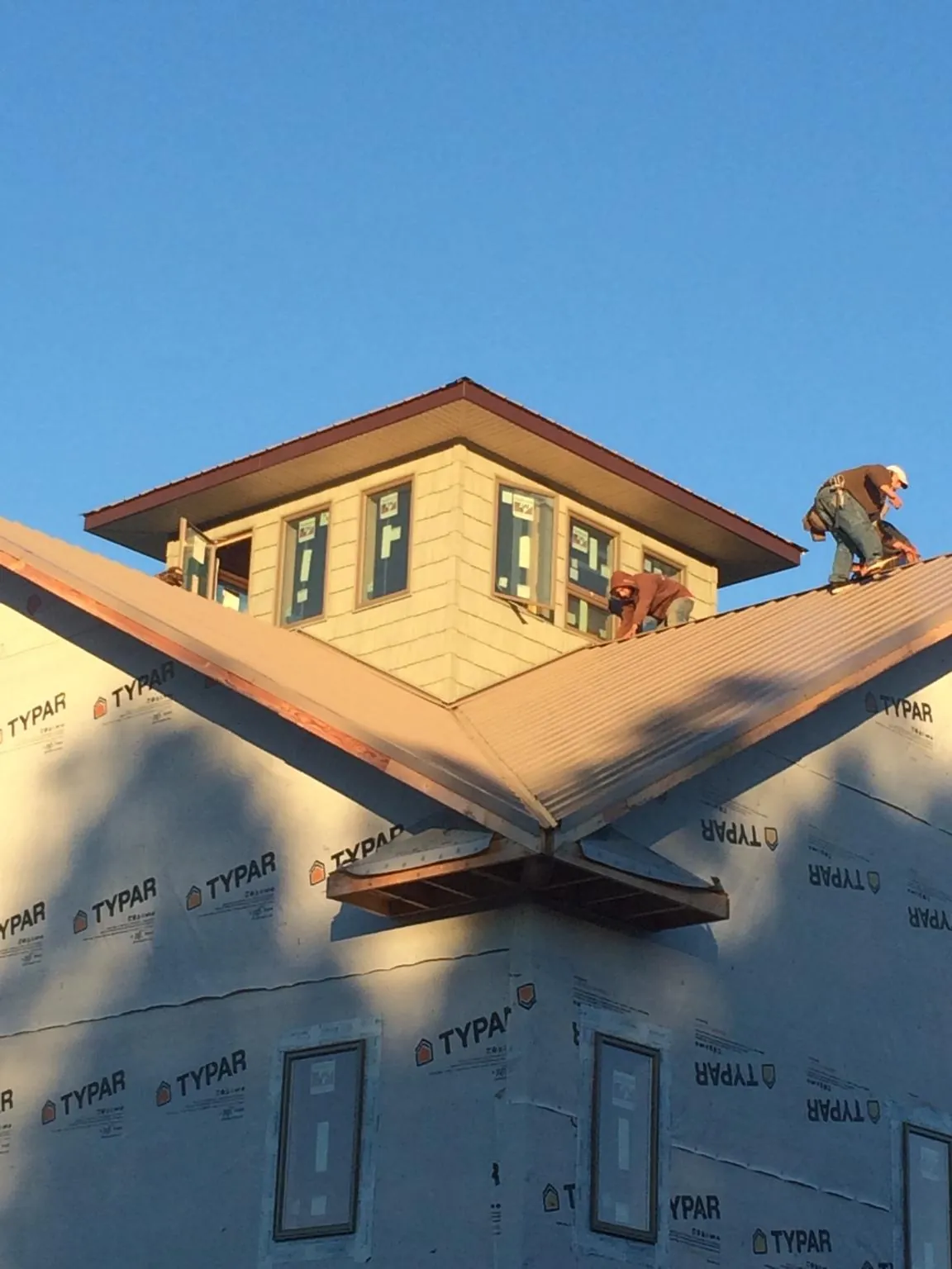 Roofers working around a rooftop cupola on a new metal roof at sunset — Roof Waterproofing in Northpoint by Roofing Brothers